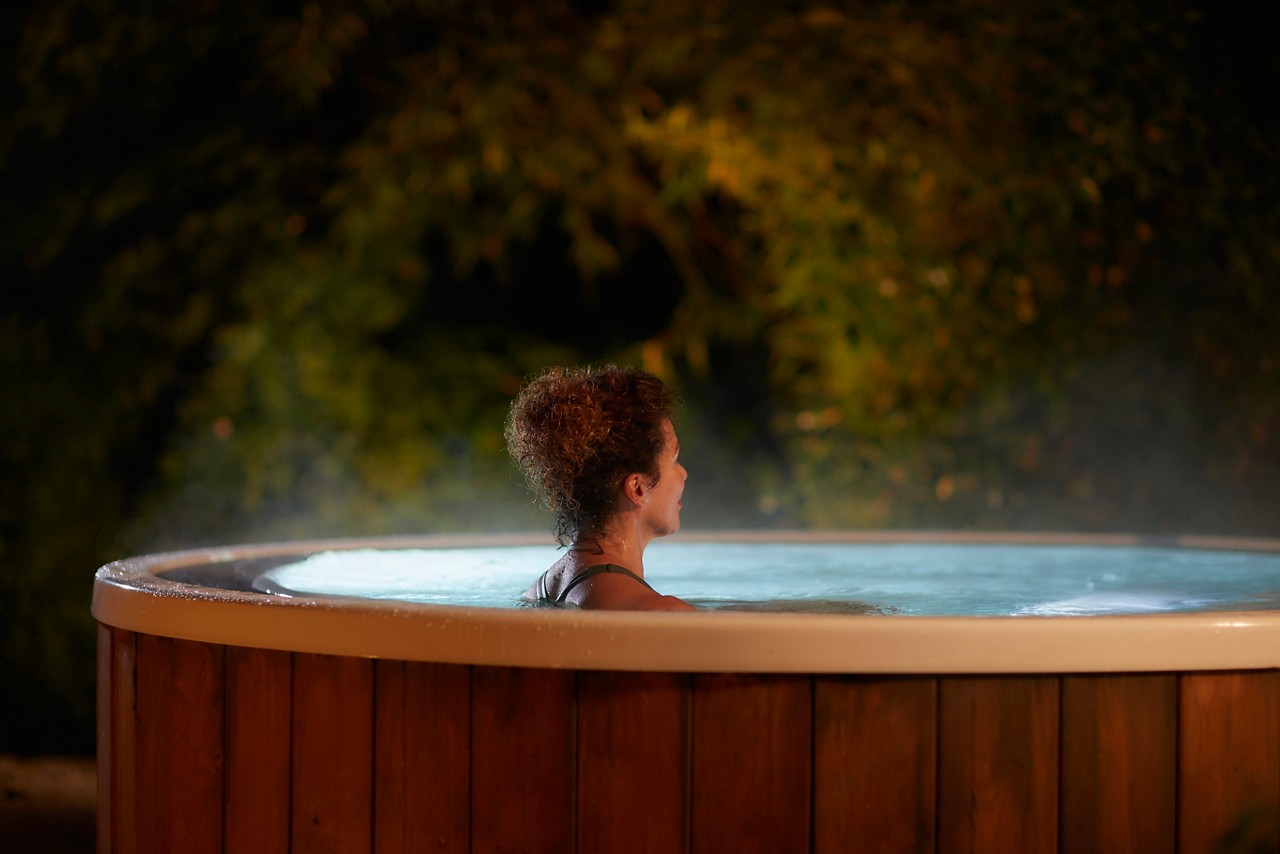 Woman soaking in a bubbling outdoor hot tub.