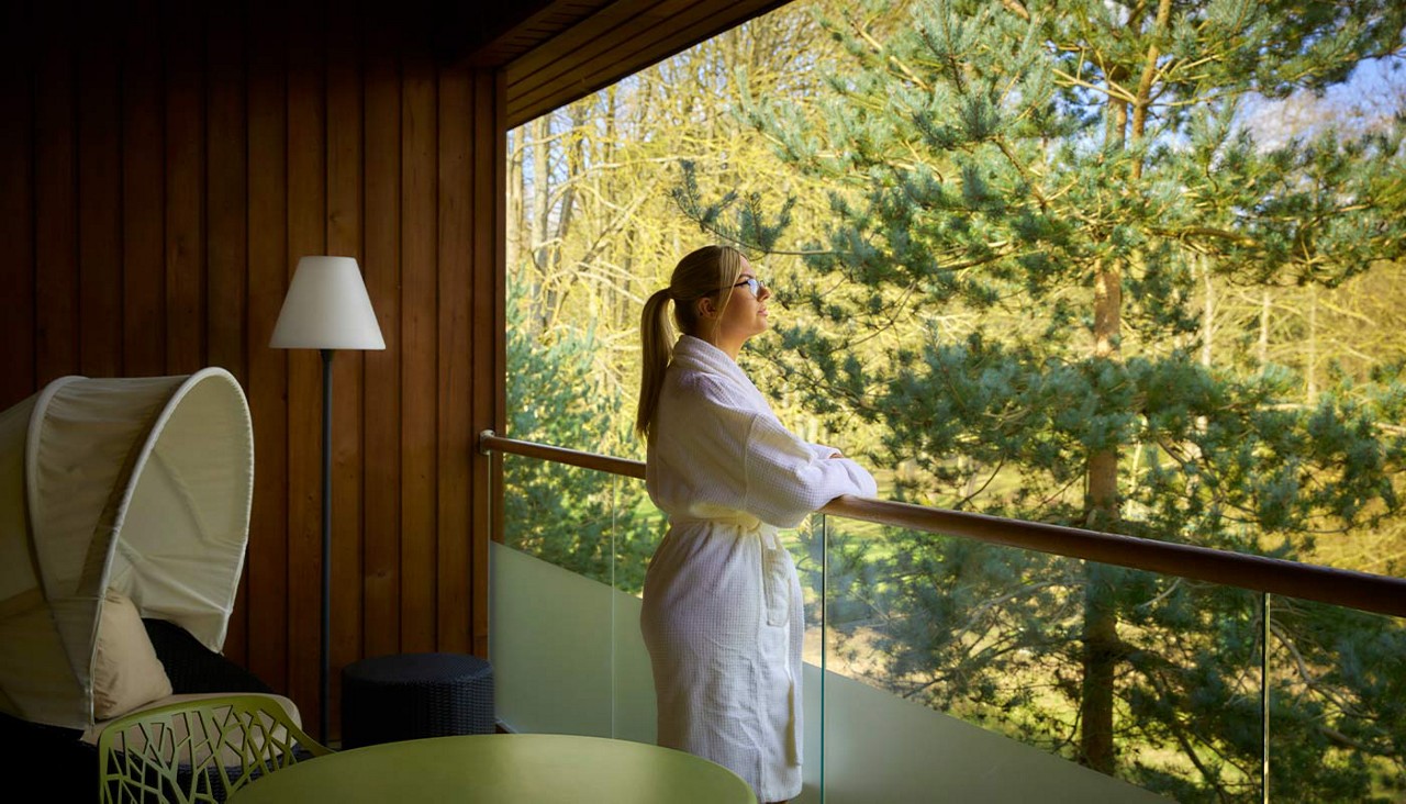 Woman looking out at the forest from a Spa Suite balcony.