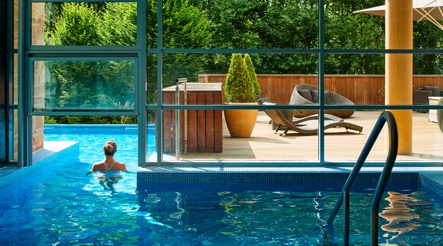 Woman soaking in an outdoor pool surrounded by the forest.