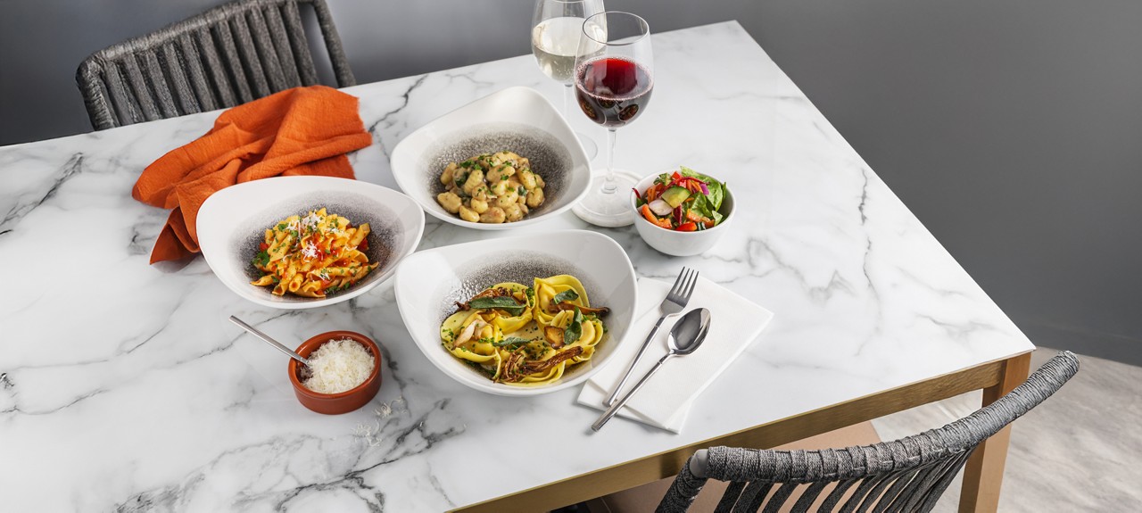 Selection of pasta dishes served with a side salad.