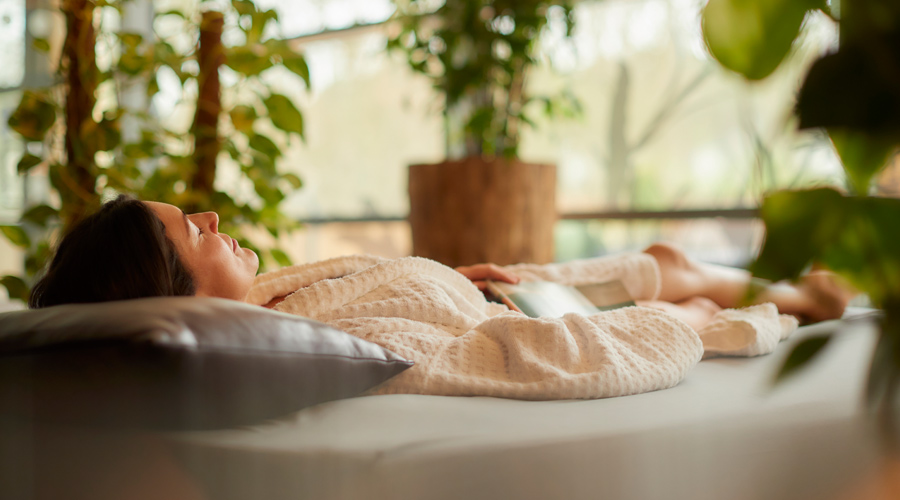 Woman resting on a waterbed in a room flooded with natural light.