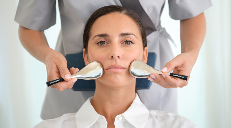 Woman having a facial with smooth, metal paddles.