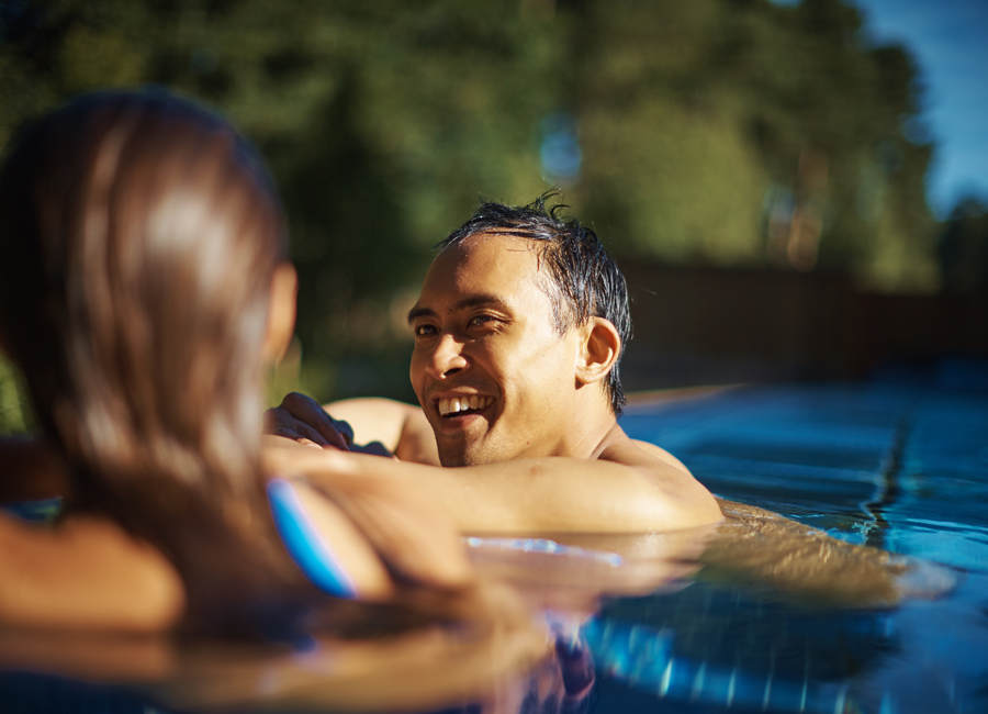 man and woman leaning on side of pool