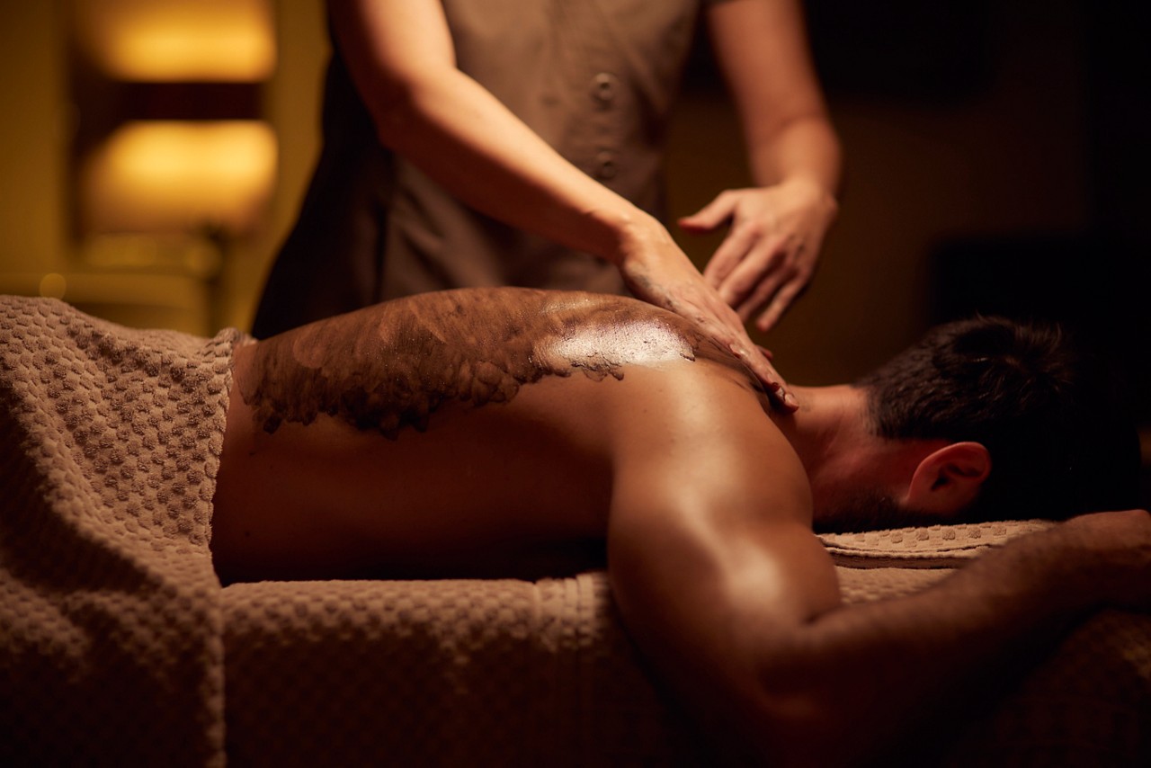 Spa therapist giving a man a relaxing back massage treatment.