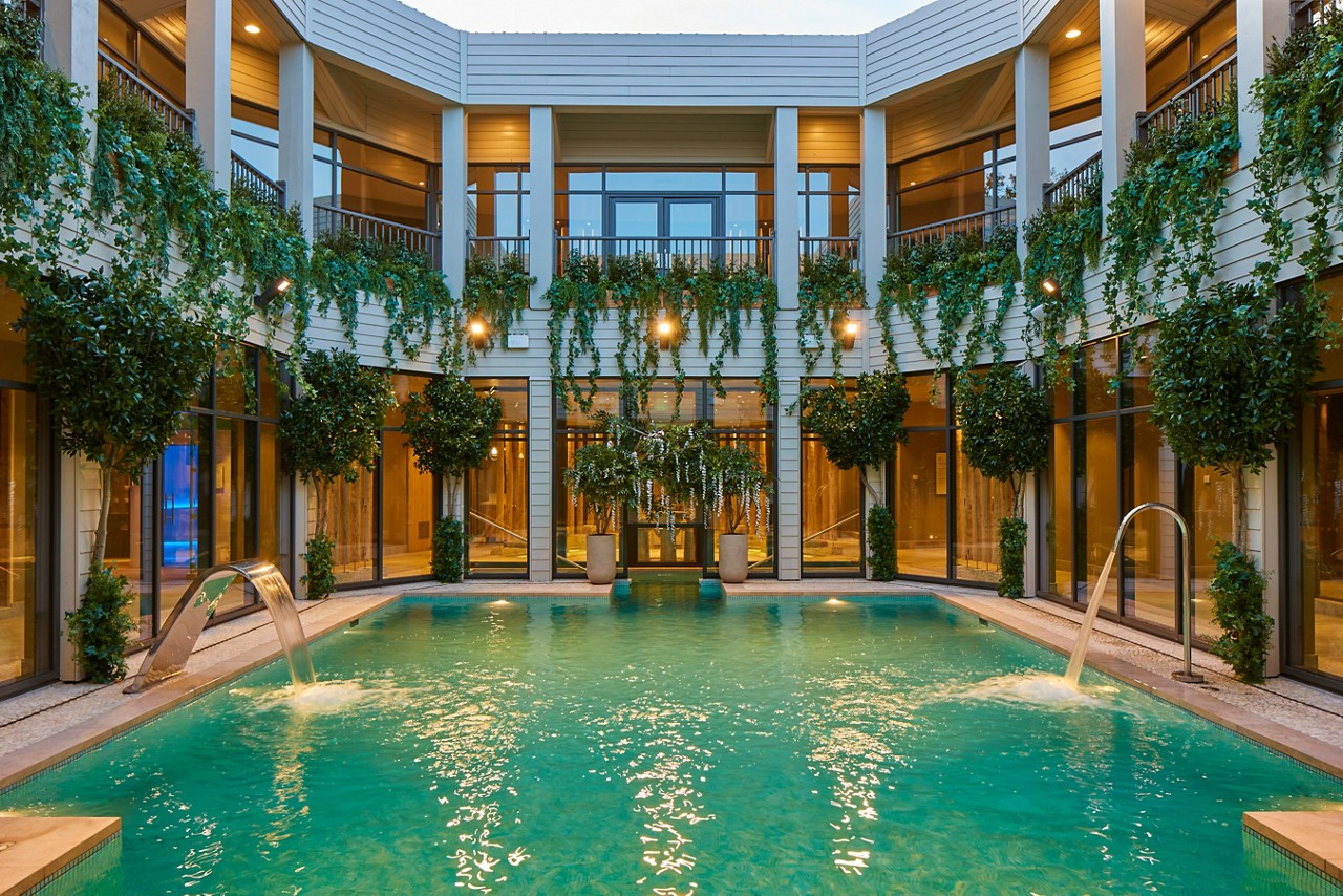Outdoor courtyard pool surrounded by hanging plants.