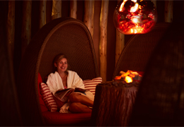 Woman sitting in a comfy chair lit by a glowing fire