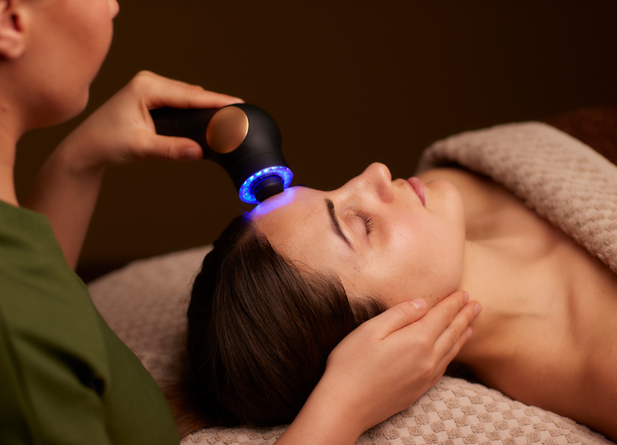 Woman having a facial with a microcurrent handheld device.