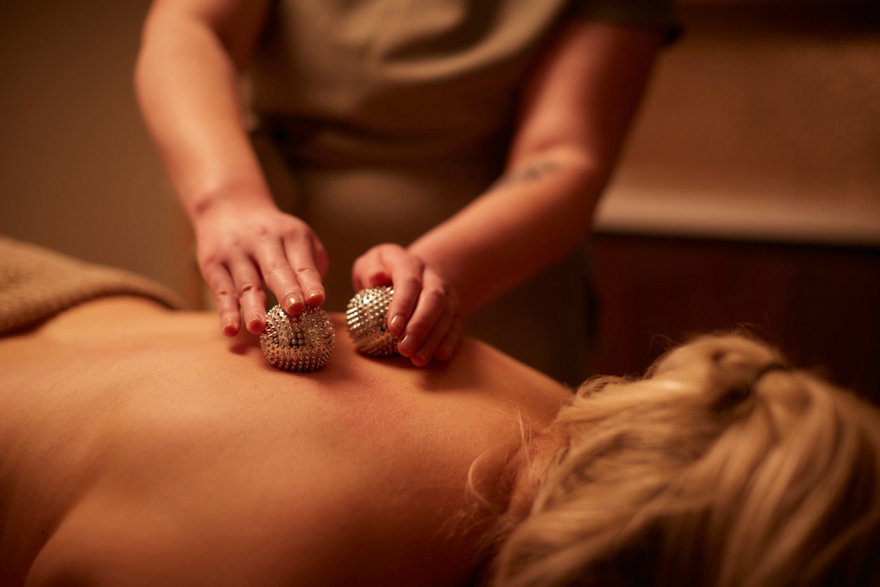 Woman having metal balls rolled against her back.