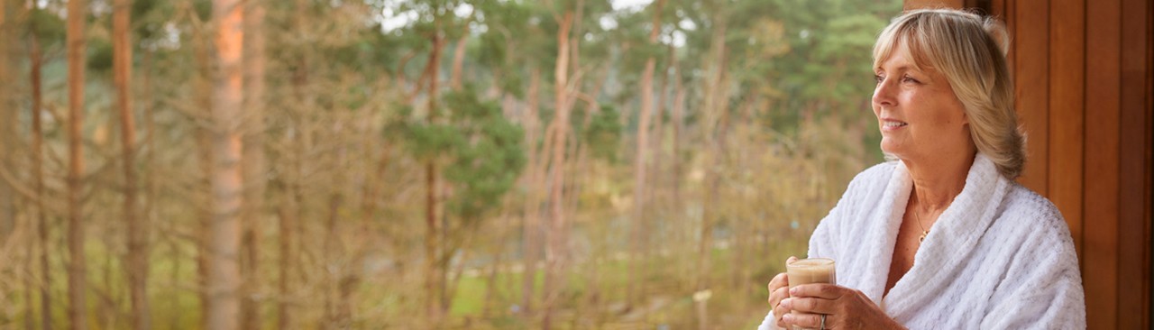 Woman enjoying the forest views, wearing a soft spa robe.