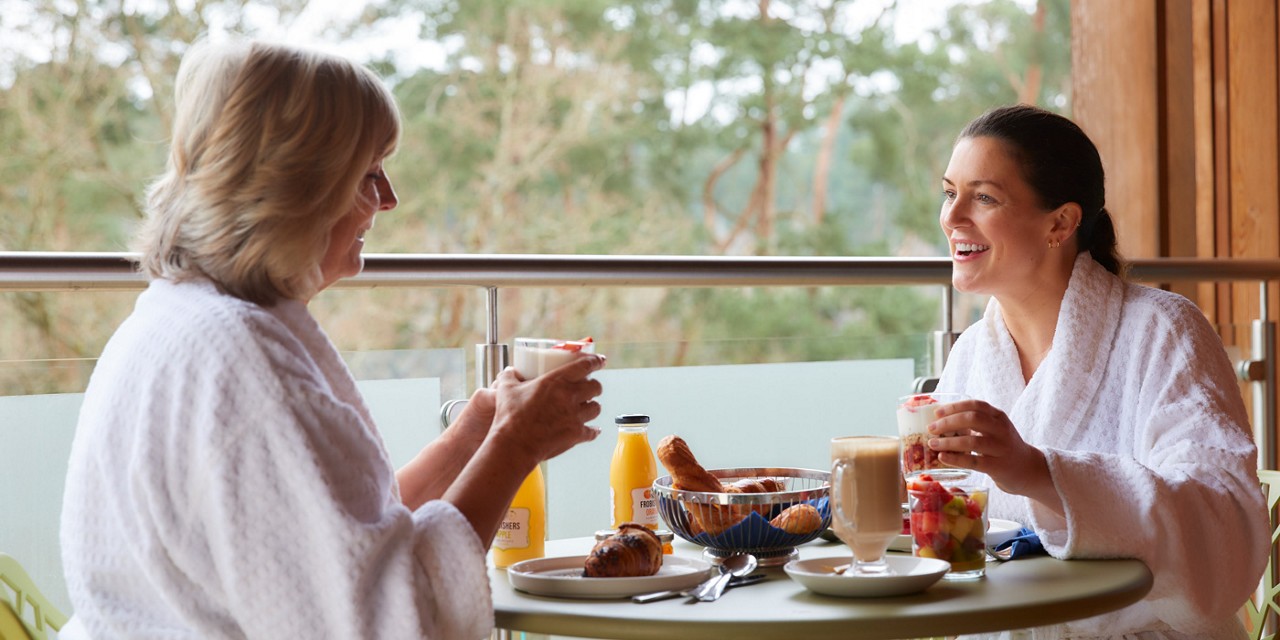 Two women enjoying breakfast on their Spa Suite balcony.