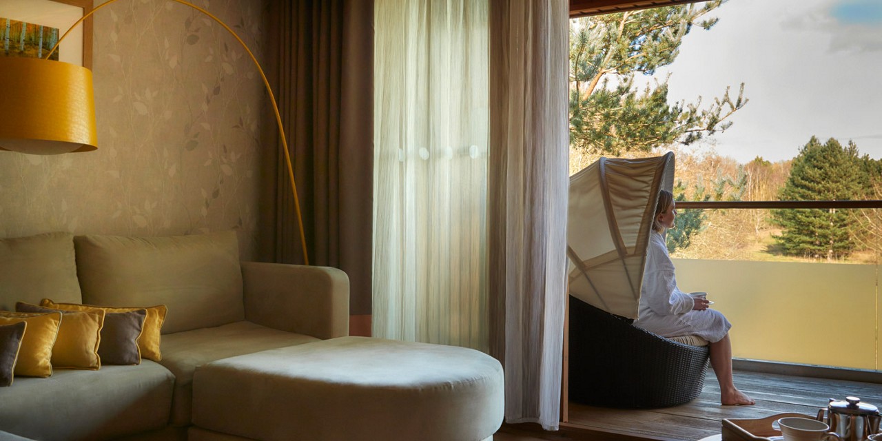 Woman sitting on a Spa Suite balcony admiring the panoramic views of the forest.