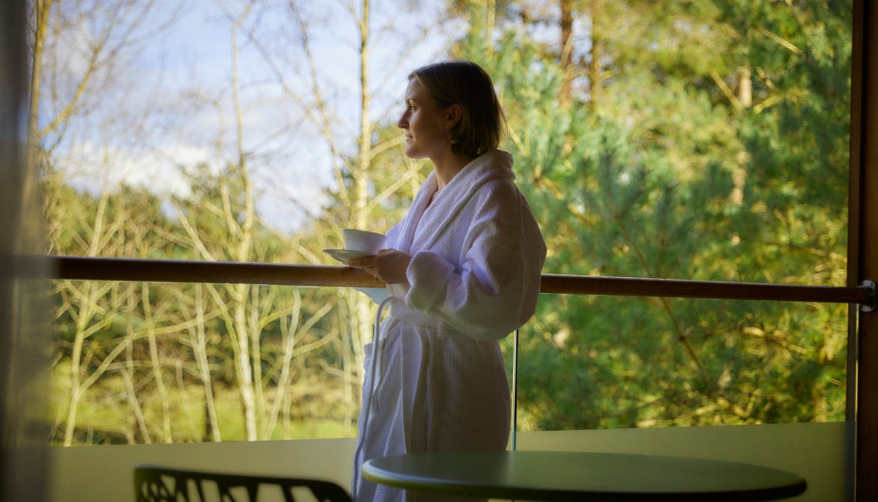 Woman looking out to the forest from a Spa Suite balcony.