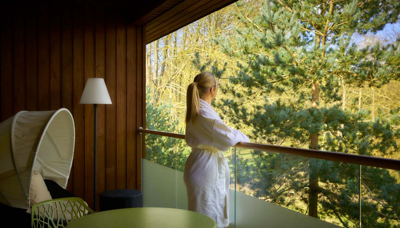 Woman look out at the forest from a Spa Suite balcony.