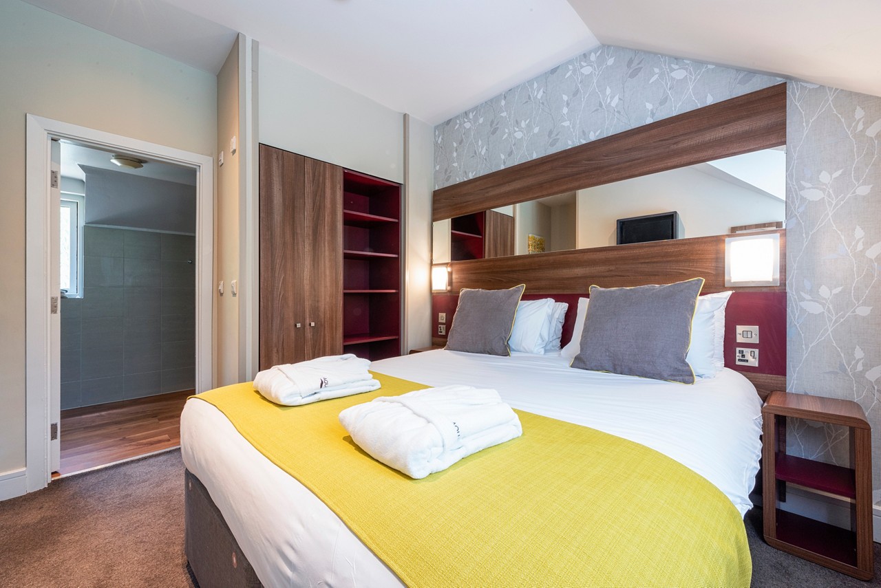 Double bed with neatly folded spa robes in a Spa Break apartment.