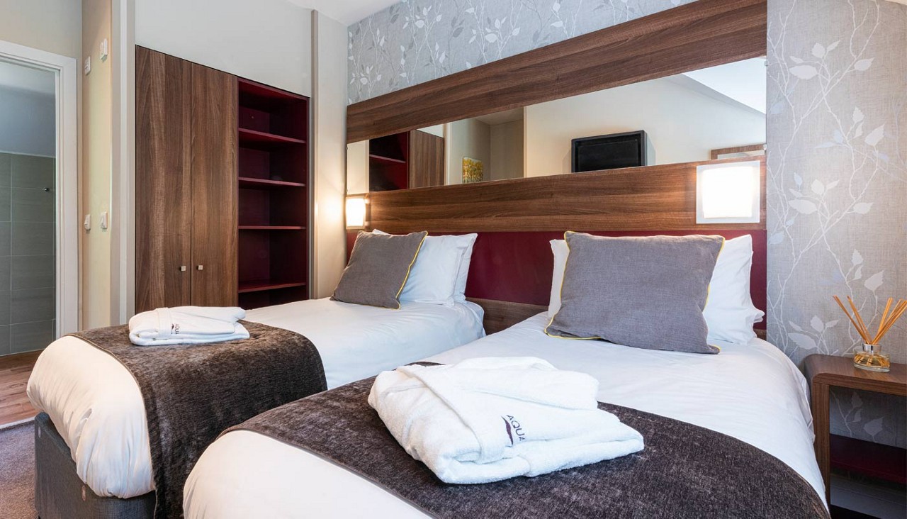 Twin beds with neatly folded spa robes.