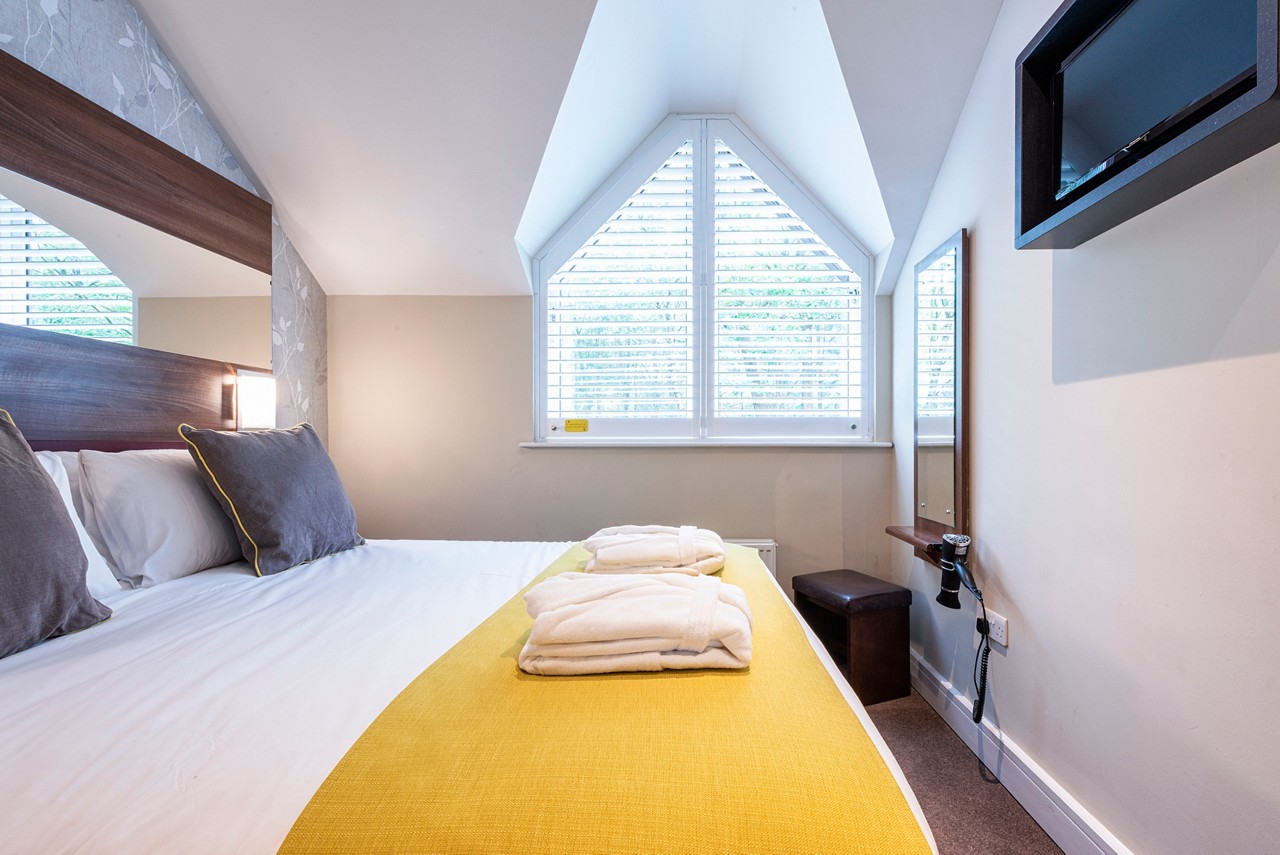 Double bed with neatly folded spa robes in a Spa Break apartment.