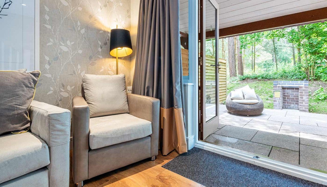Living space with views out to an outdoor terrace surrounded by the forest.