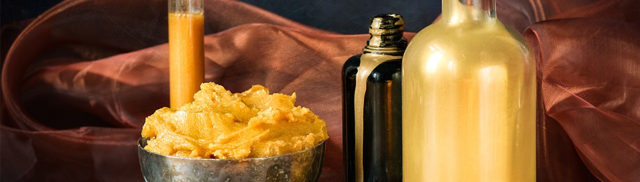 gold liquid in bottles, gold scrub in a bowl