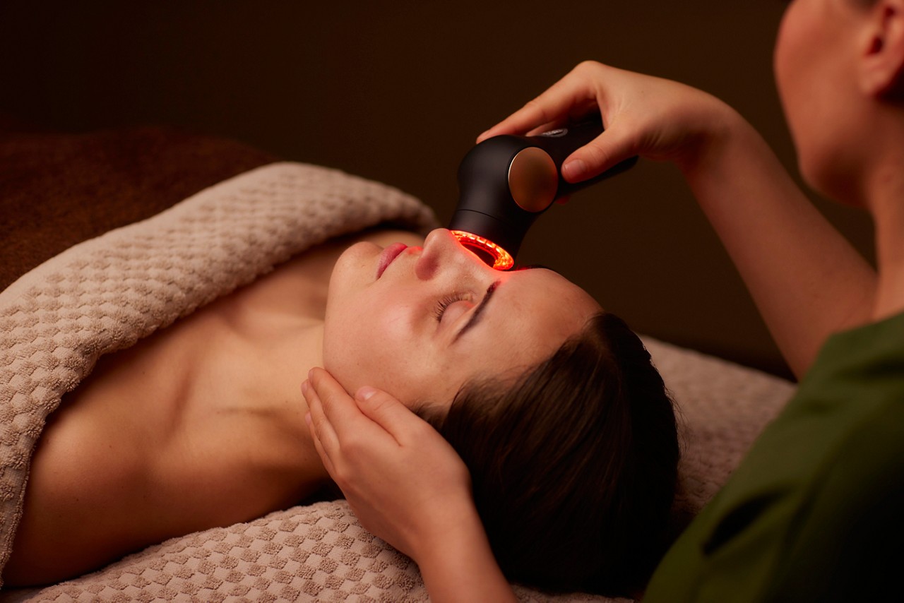Spa therapist giving a woman a Theraface microcurrent facial treatment.