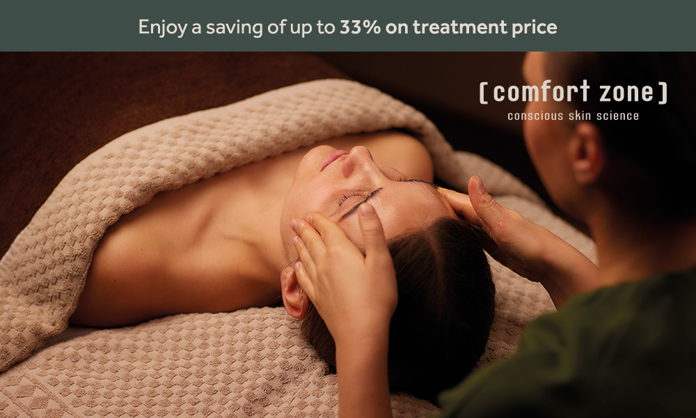 Women lying on a spa bed with a blanket over her whilst spa therapist gives her a facial