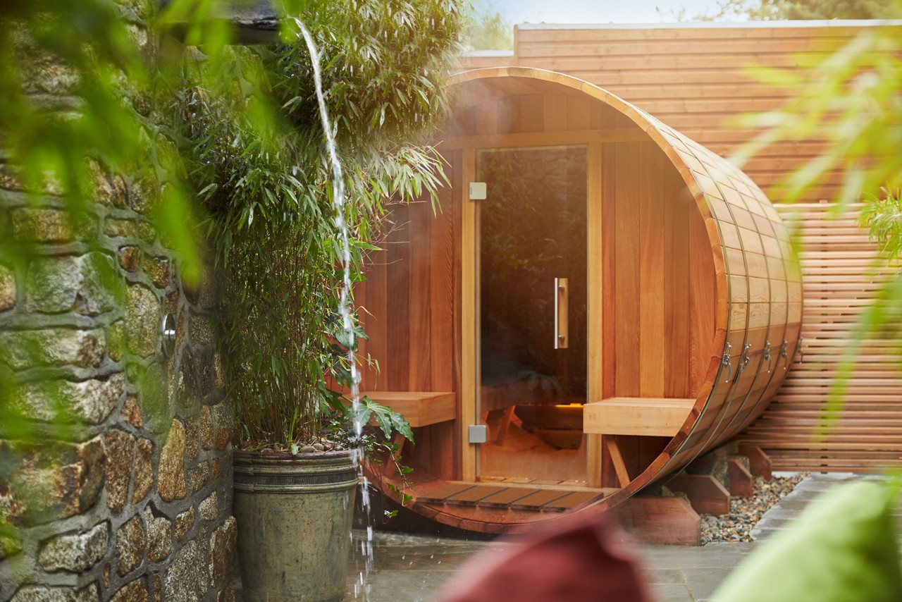 Private barrel sauna surrounded by lush trees in an open-air courtyard.