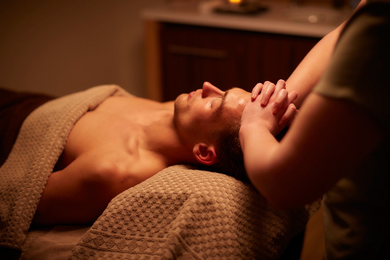 Spa therapist giving a man a relaxing massage treatment whilst lying on a spa bed