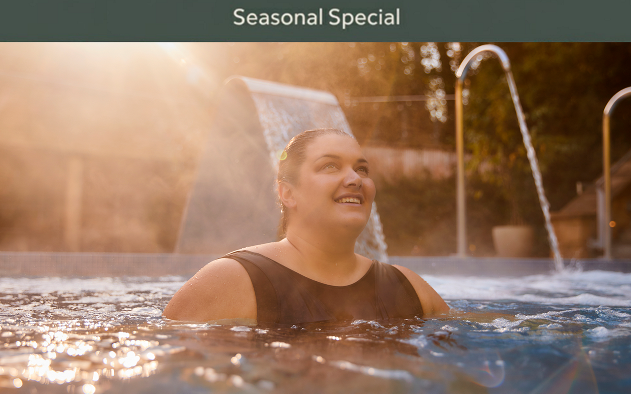 Woman soaking in an outdoor pool surrounded by the forest.