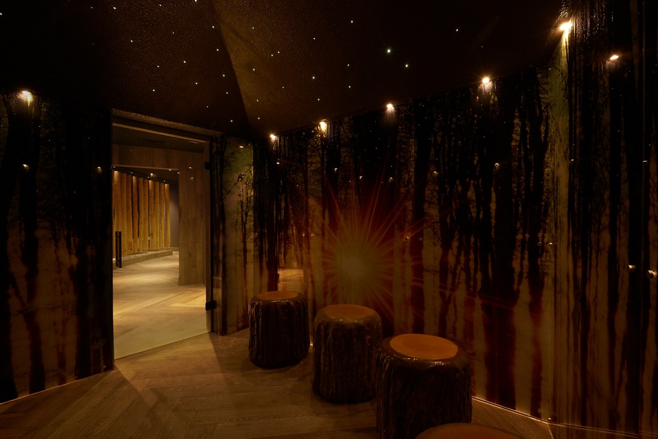 Forest themed steam room with tree trunk seating and twinkling lights.