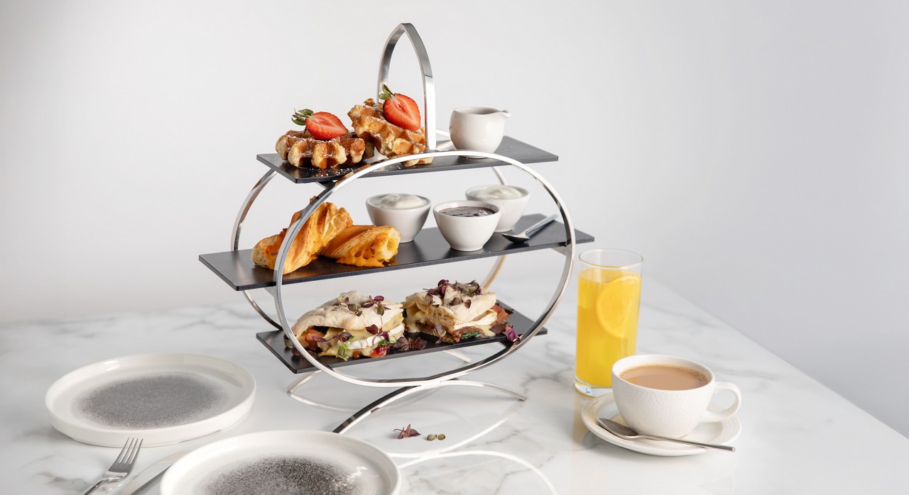 Breakfast platter served with a glass of fresh juice and a hot drink