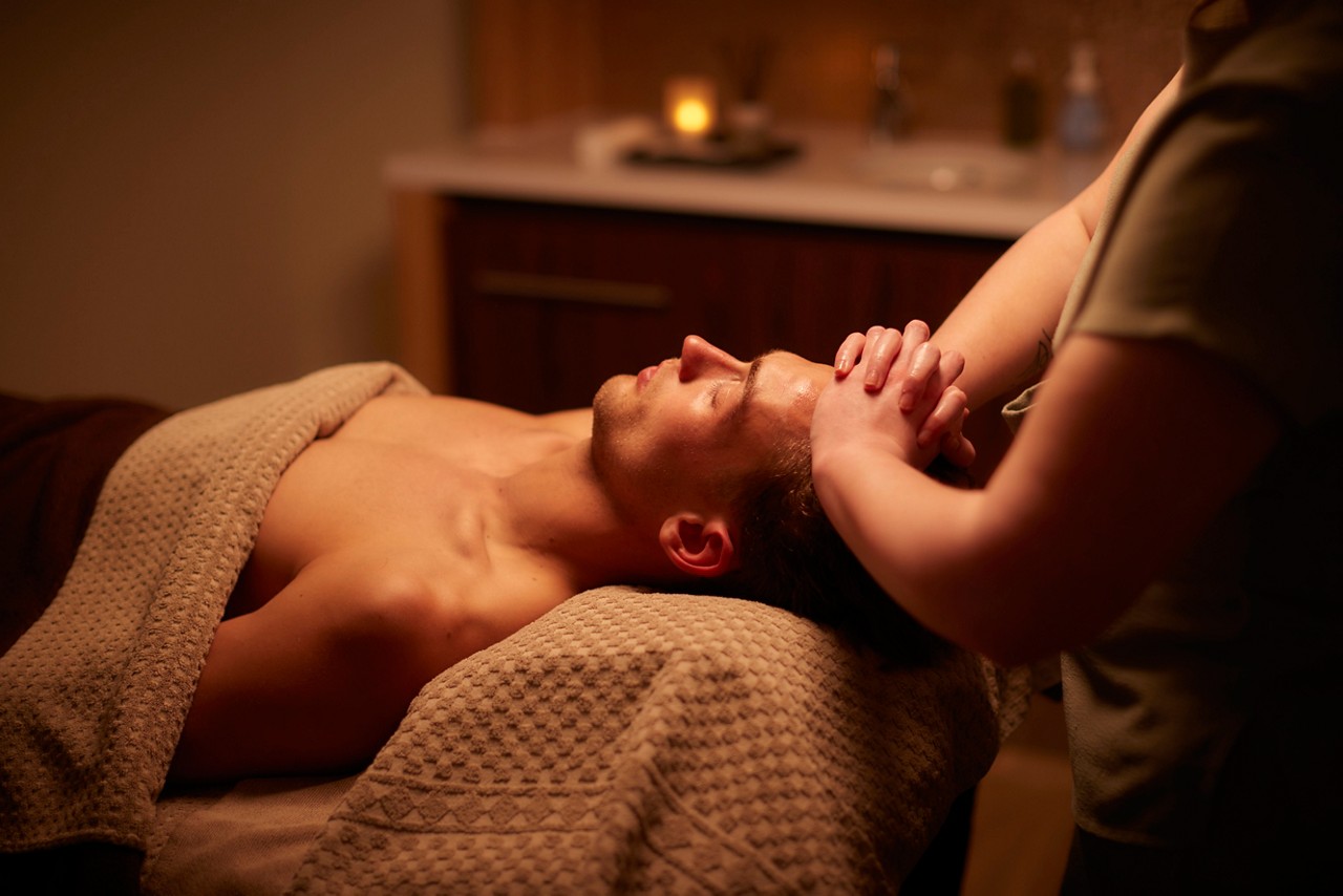Spa therapist giving a man a relaxing massage treatment whilst lying on a spa bed