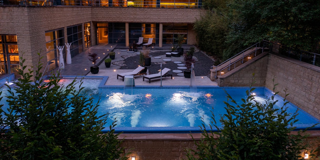 Outdoor pool in the evening, surrounded by the forest.