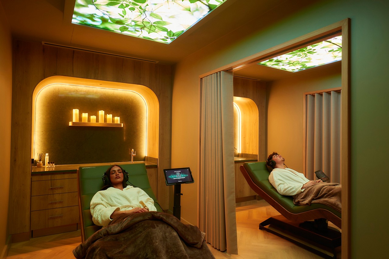 two people in spa robes lying on a spa bed with headphones on a blanket