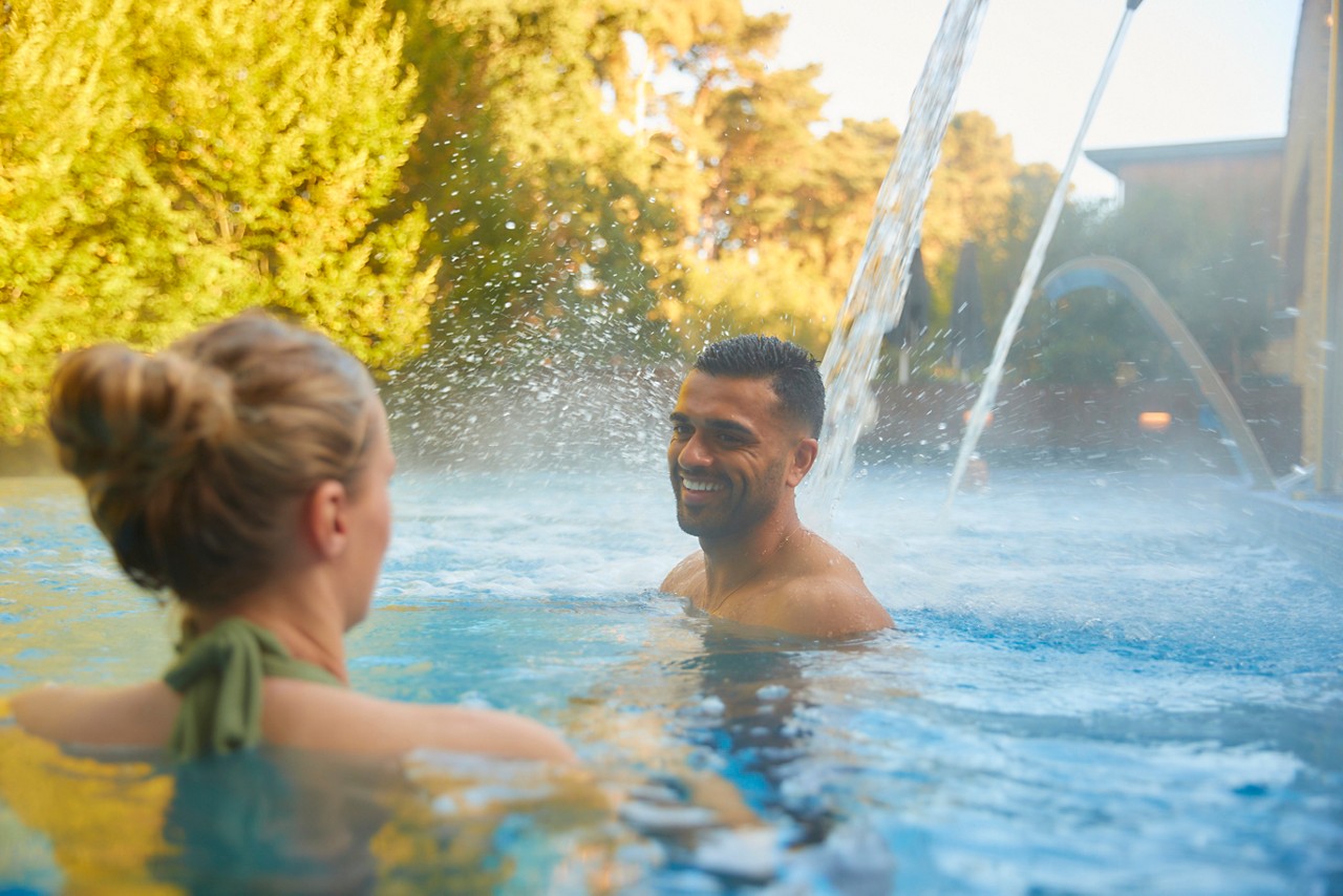 Man and woman soaking under flowing water.