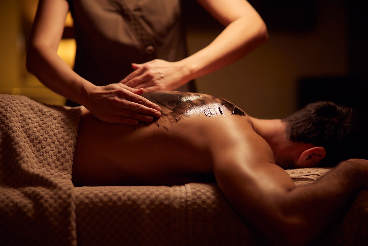 Spa therapist giving a man a relaxing back massage treatment.