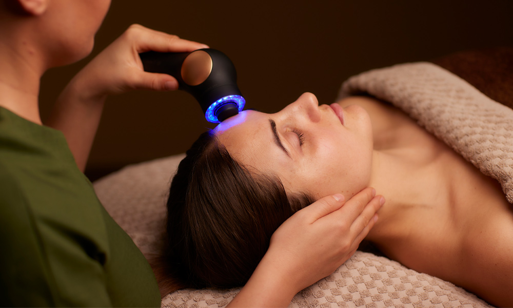 Woman having a facial with a microcurrent handheld device.