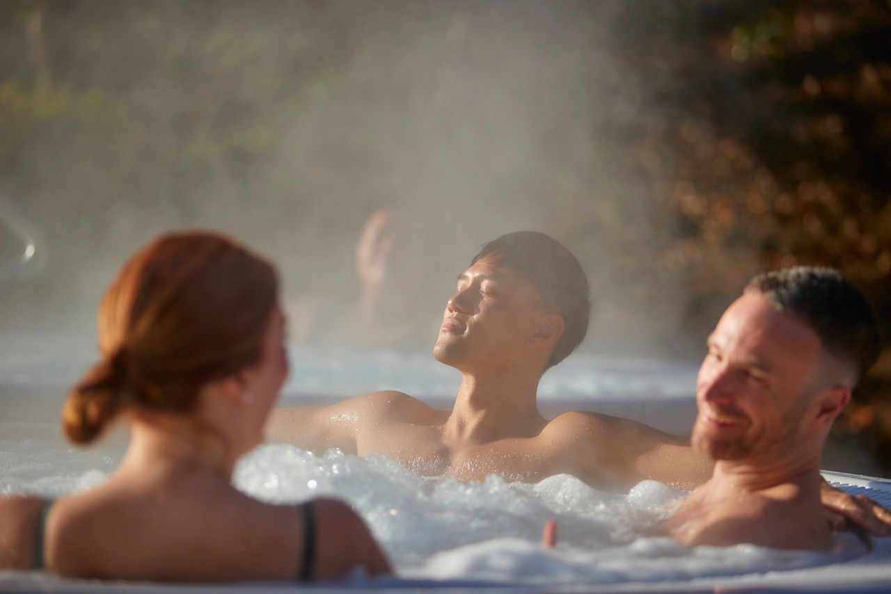 three people in an outdoor hot tub with steam surrounding them