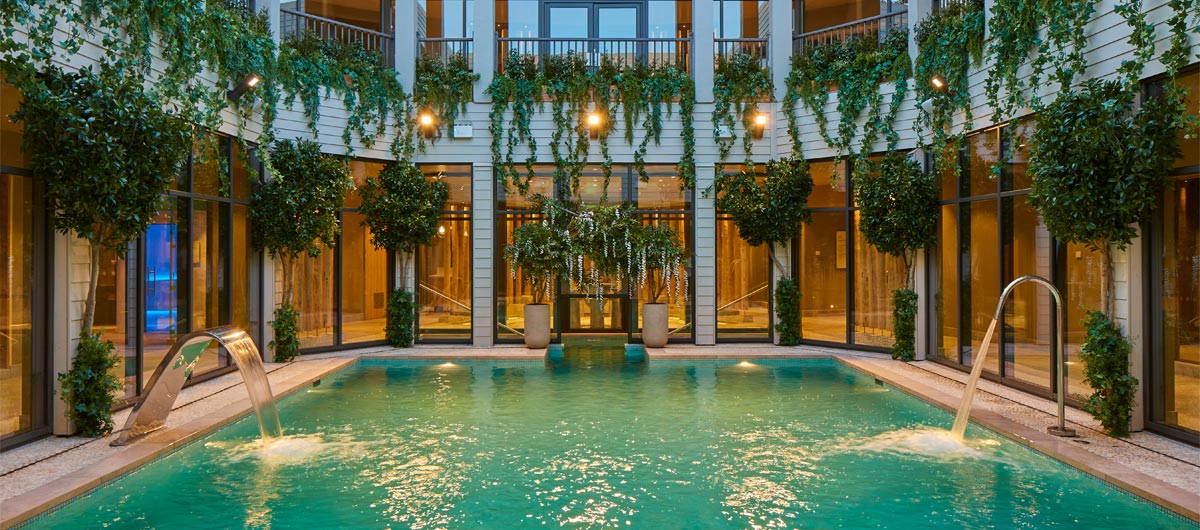 Outdoor courtyard pool with lots of hanging plants.