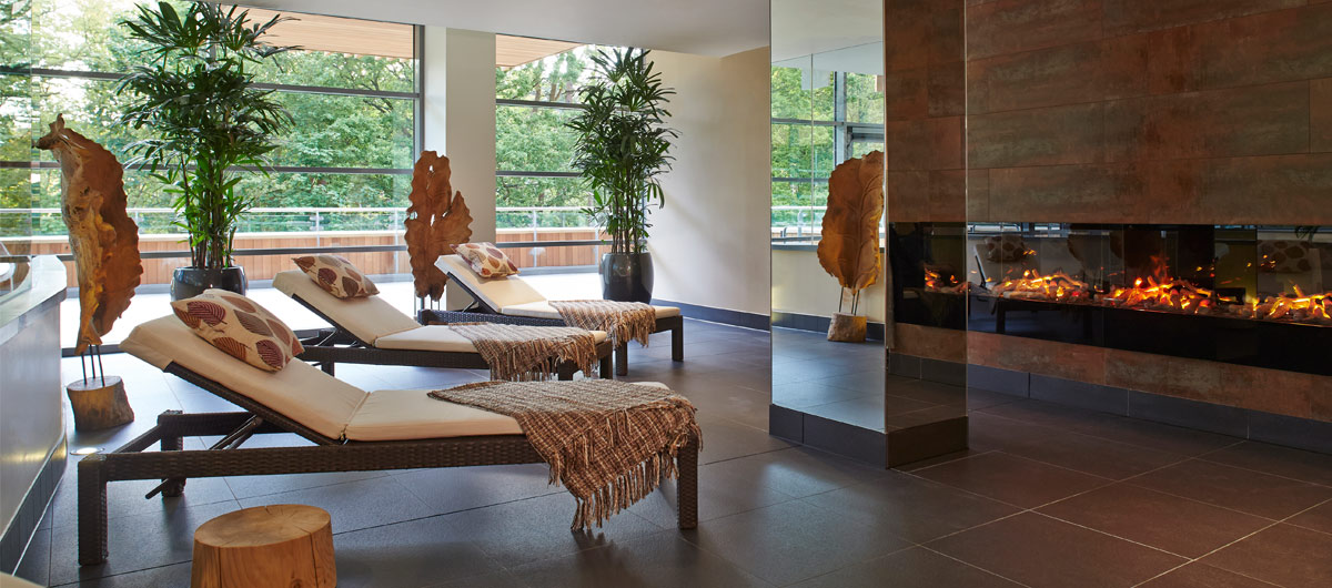3 lounge chairs in front of fire with blankets