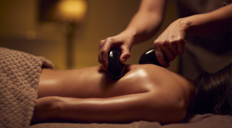 women receiving a back massage using stones