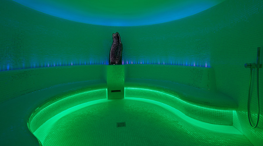 steam room with green lighting and bench around the wall