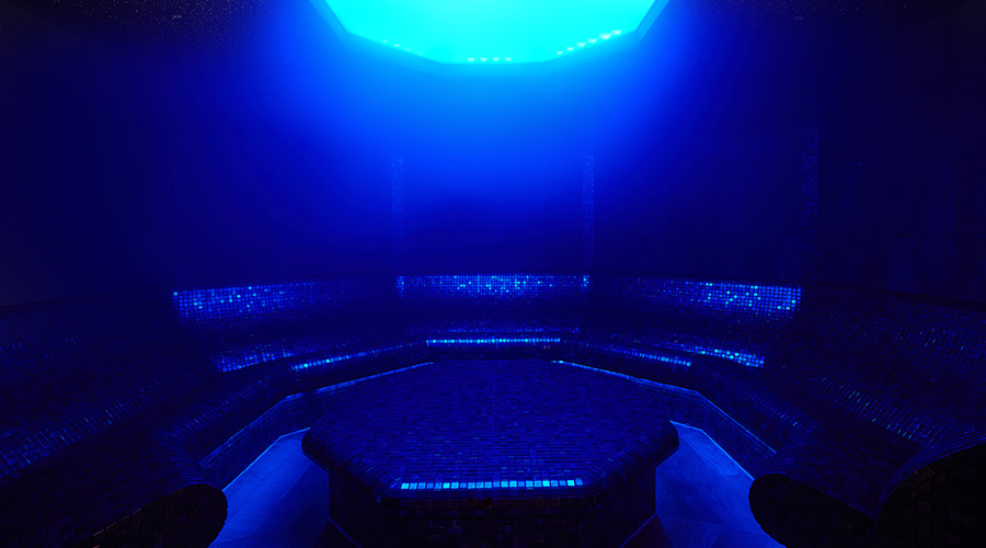 steam room with tiled seats and blue lighting