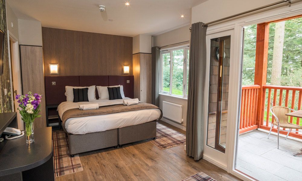 Spa Apartment with a double bed, balcony and views out to the surrounding forest.