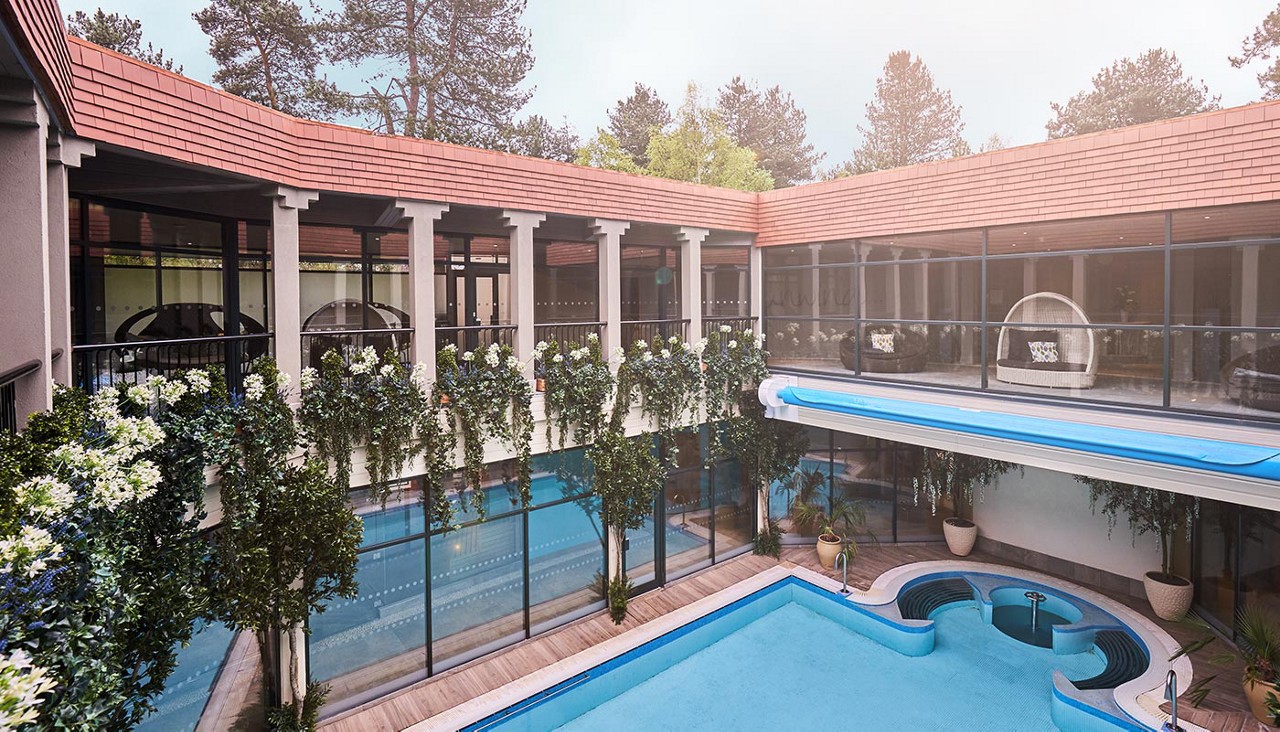Outdoor courtyard pool with lots of hanging plants.