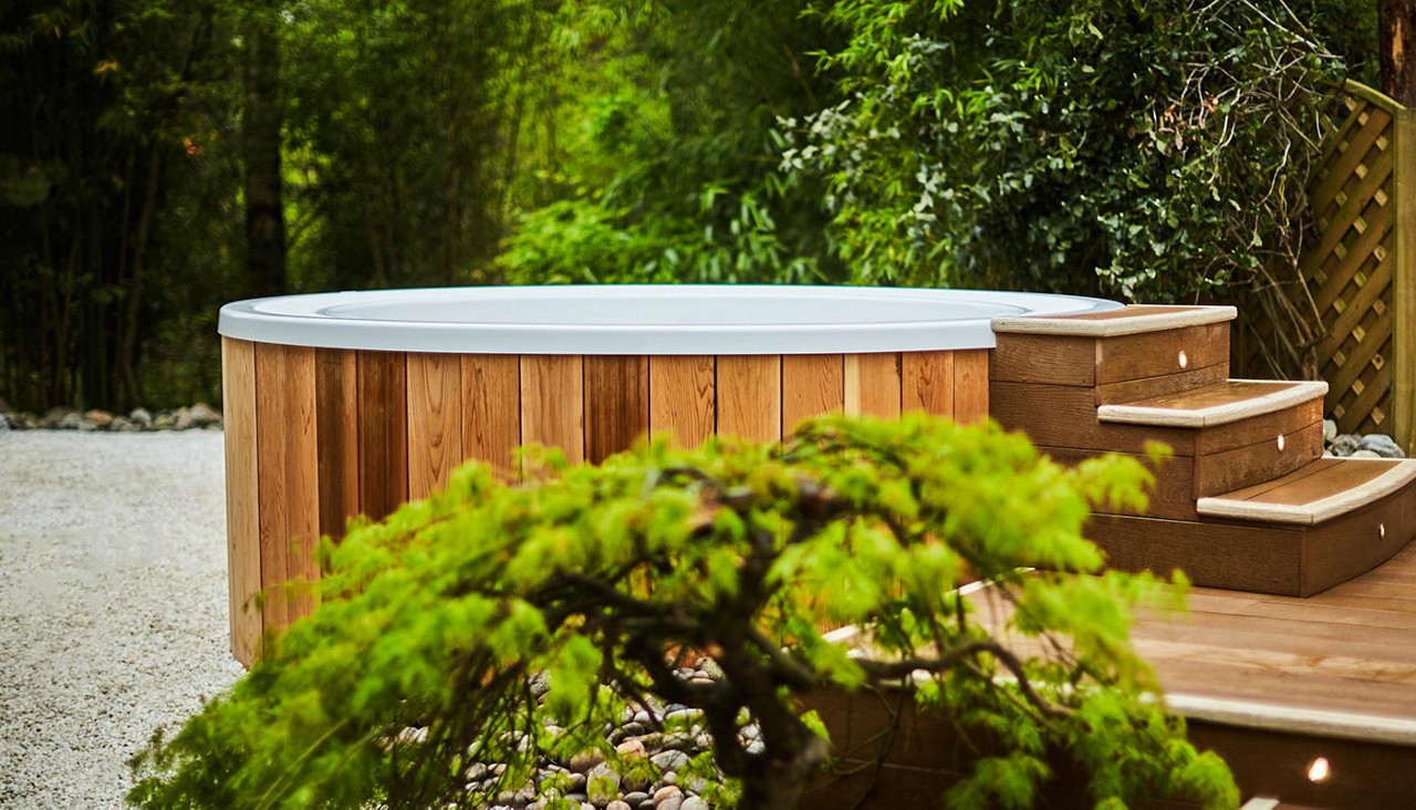 Outdoor hot tub surrounded by decorative garden pieces.