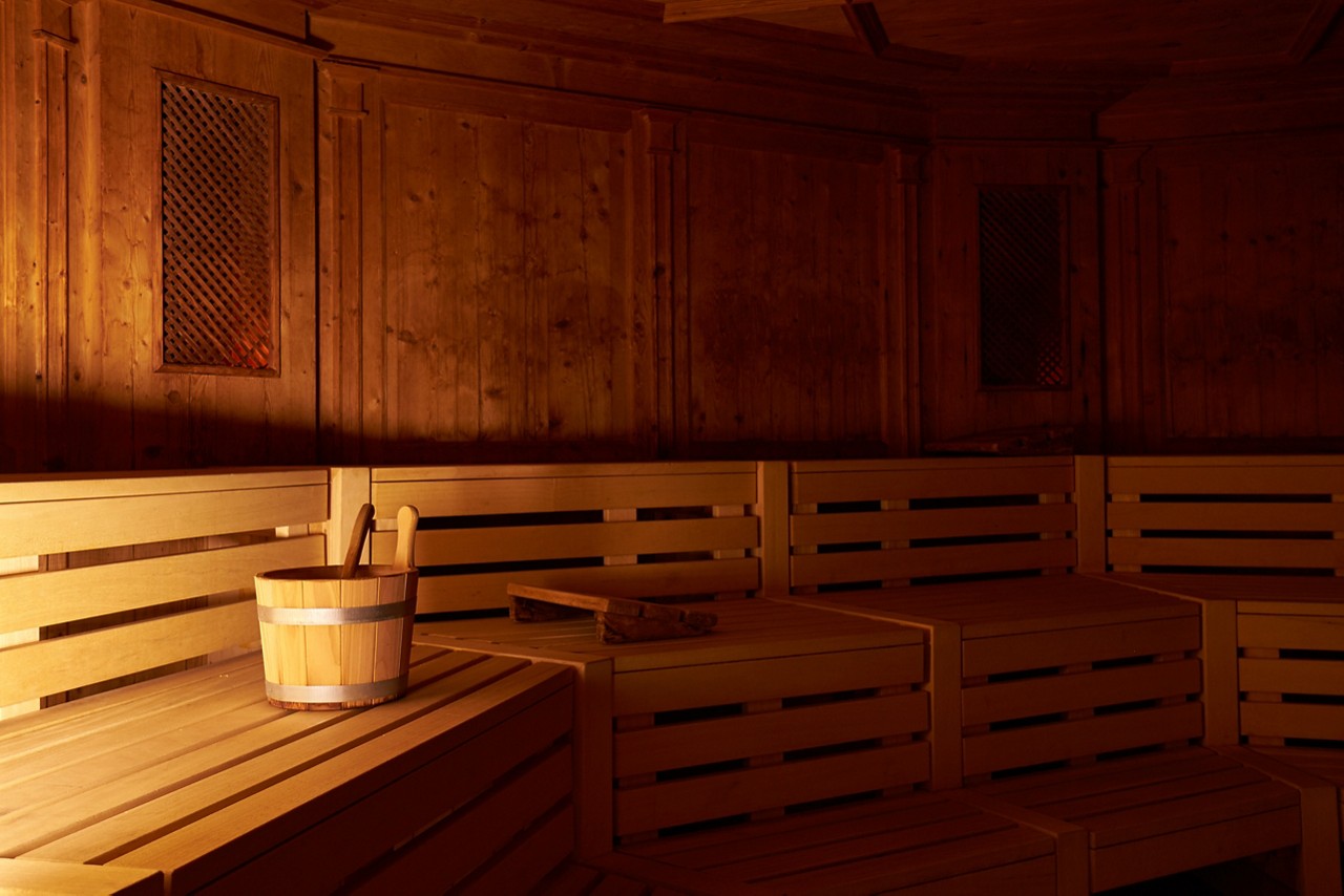 Wooden Tyrolean Sauna with bench seating and a bucket of cold water.