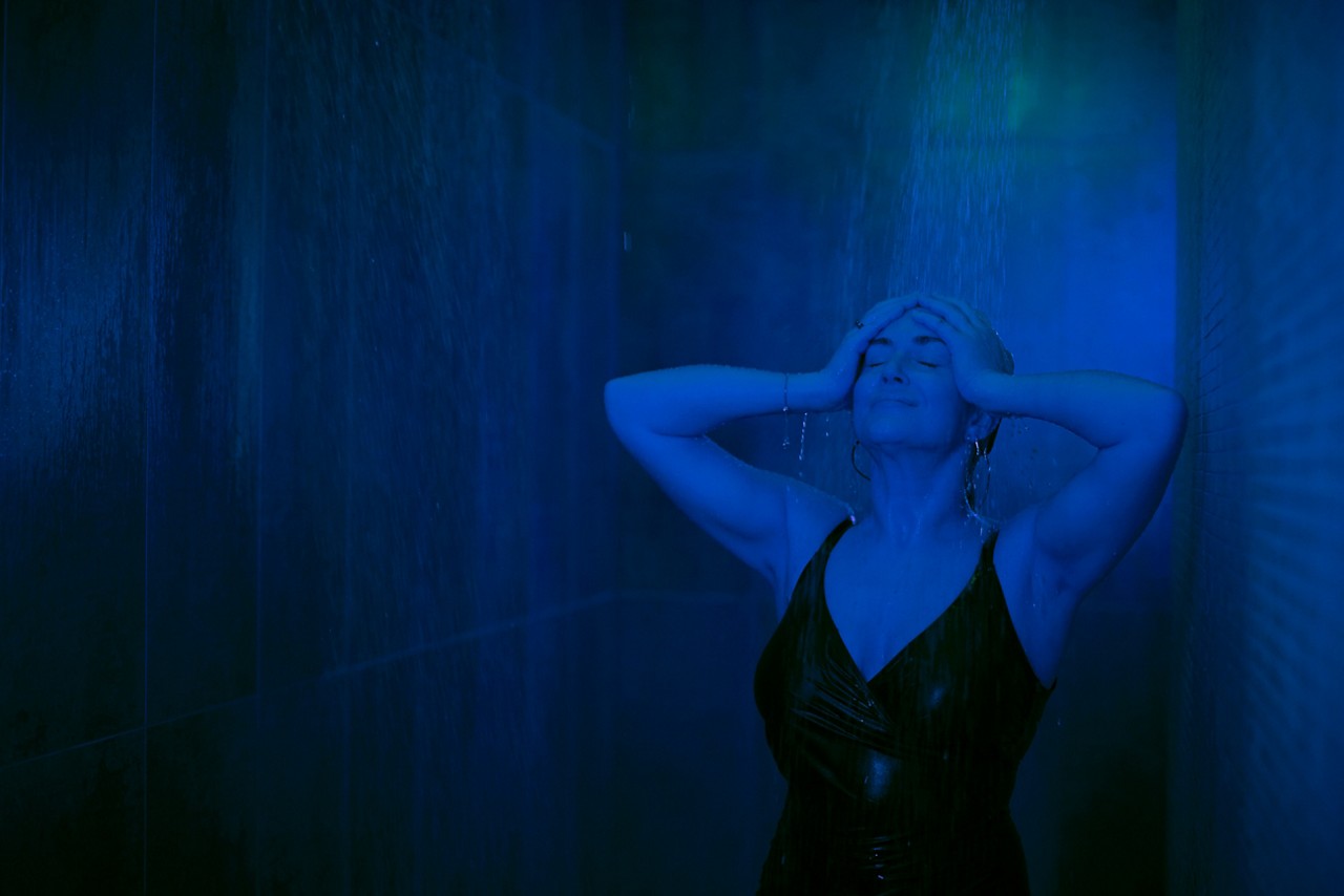 Woman standing under the Rain Walk shower with water flowing over her head.