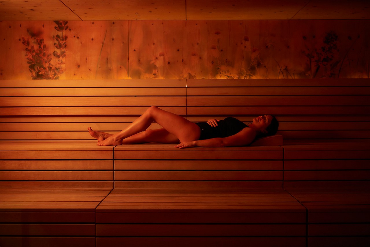 Woman laid on a wooden bench in the Herbal Sauna.