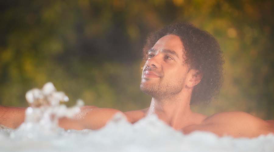 Man soaking in a bubbling outdoor hot tub.