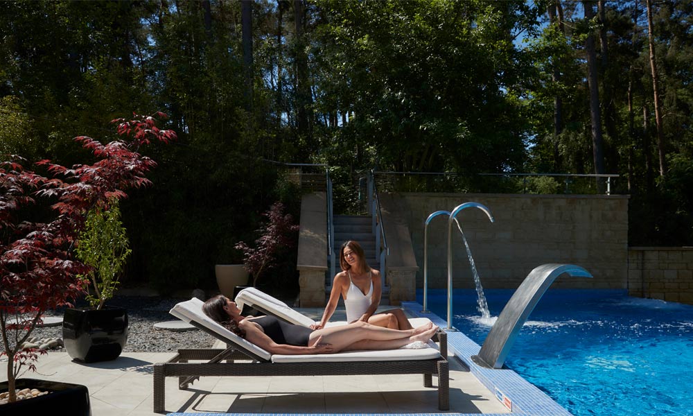 Two women on loungers by the side of outdoor pool