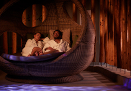 Couple snuggled in a large, cosy cocoon chair.